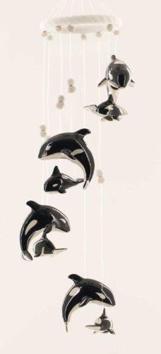 an orca whale crib mobile hanging from the ceiling in a white room with three dolphins on it