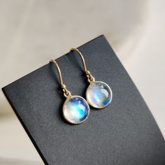 ITEM DESCRIPTION: >> The earrings are made from Solid 14K Yellow Gold. Gemstone used is absolutely natural and ethically sourced. >> Natural Rainbow Moonstone in round shape and cabachon cut with bezel setting is studded on it with utmost precision.  >> This is a minimalist design and is absolutely hassle-free and everyday jewelry.  Gem: Rainbow Moonstone Gem size: 8 mm round Gem weight: 4.22 carats Gold purity: 14K (58.33% approx.) Gold weight: 0.57 grams  Gross weight: 1.41 grams The Gold purity is guaranteed and it comes with authentic 14K gold hallmark. Since these Earrings are handmade, they are Nickel/Lead FREE.  CUSTOMIZATION: --> You can choose your own gemstone. --> Kindly drop a message for more options. CUSTOMER SUPPORT: We are available 24/7 to respond to all your queries!  PAC Moonstone Round Yellow Gold Earrings, Round Moonstone Yellow Gold Earrings, Moonstone Yellow Gold Round Earrings, Gift Dangle Earrings With Bezel Setting, Yellow Gold Round Moonstone Earrings, Round Gold Moonstone Earrings, White Bezel Setting Earrings For Gift, 14k Gold Filled Round Gemstone Earrings, Handmade Jewelry Box