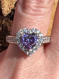 The purple cubic zirconia in this ring has a measurement of approx. 7.8mm x 7.5mm. The other cubic zirconias in this ring have a measurement of approx. 1.9mm. The back of shank has a measurement of approx. 3.4mm. This ring weighs approx. 4.7 grams. Size: 8 US. Stock number: 257 Dazzling Cubic Zirconia Heart Ring For Anniversary, Heart-shaped Cubic Zirconia Ring With Prong Setting, Heart Shaped Cubic Zirconia Ring With Prong Setting, Purple Heart Cut Cubic Zirconia Jewelry, Purple Heart Ring With Accent Stones For Anniversary, Anniversary Purple Heart Ring With Accent Stones, Cubic Zirconia Heart Ring With Center Stone, Dazzling Cubic Zirconia Heart Ring With Brilliant Cut, Heart Cut Cubic Zirconia Ring With Halo Setting