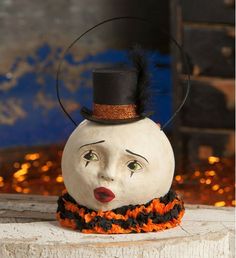 a white pumpkin with a black top hat and orange scarf around it's neck