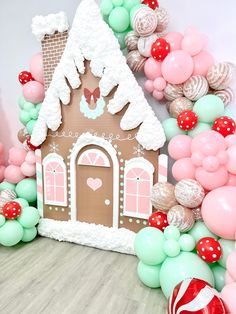 a gingerbread house is surrounded by balloons and streamers for a christmas themed party