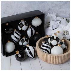 black and white ornaments are in a wooden bowl on the floor next to a box