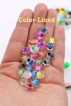 a hand holding a bunch of colorful beads in it's palm with the words color - lined