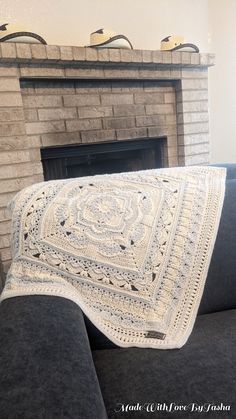 a white crocheted afghan sits on a couch next to a fireplace