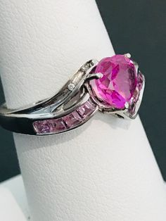 This striking heart shape pink cubic zirconia ring is handmade in sterling silver and is complete with princess cut light powder pink cubic zirconias and two natural white diamond accents. The vibrancy of the center stone will make your mouth water! The design was meticulously thought out as it includes two hearts on each side of the ring in filigree metal work. Can be sized up or down for an additional charge. Feel free to contact us with any questions you may have. Dazzling Pink Sterling Silver Ring, Pink Diamond Rings With Diamond Cut, Pink Fine Jewelry Promise Ring, Pink Sterling Silver Diamond Ring With Accent Stones, Pink Diamond Cut Diamond Ring, Pink Sterling Silver Diamond Ring With Vs Clarity, Pink Diamond Ring With Vs Clarity In Sterling Silver, Pink Diamond Ring In Sterling Silver With Vs Clarity, Pink Diamond Promise Ring In Fine Jewelry Style