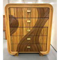 an art deco dresser with wooden drawers and brass hardware on the top, in front of a white wall