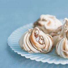 three small shells sitting on top of a white plate with blue table cloth behind them