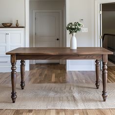 a wooden table sitting on top of a hard wood floor next to a white door