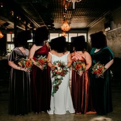 four bridesmaids stand in a row with their bouquets