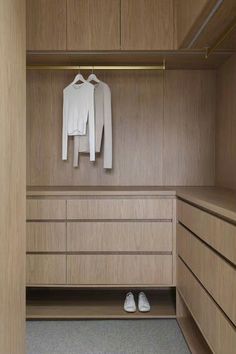 an empty closet with shoes and sweaters hanging on the clothes rack, next to a pair of white sneakers