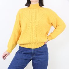 Item Description  Super cute knit pullover sweater! Love the marigold yellow color, and the details throughout; the ribbed mockneck, the unique aran style cable knit design on the front, and the heavy high quality feel of the all-cotton material. Love the comfy fit and the versatility of a sweater like this! It is in excellent condition with no flaws to note.  Item Specifics  Brand - Across America  Material - 100% cotton Color - Marigold yellow Measurements  Shoulder to Hem - 24 in.  Sleeve Len Retro Cable Knit Sweater For Fall, Retro Chunky Knit Sweater For Fall, Retro Chunky Knit Fall Sweater, Vintage Solid Sweater For Fall, Vintage Sweater For Fall, Vintage Solid Color Sweater For Fall, Solid Vintage Sweater For Fall, Yellow Turtleneck Sweater For Fall, Vintage Crew Neck Chunky Knit Sweater