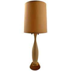 a table lamp with a beige shade on it's base and a wooden base