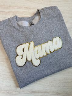 This cozy MAMA white chenille patch sweatshirt is the perfect crewneck sweatshirt for your favorite mama!  Gildan Unisex Sweatshirt - Air-jet spun yarn for a soft feel and reduced pilling! * 50% cotton, 50% polyester * Pre-shrunk * Classic fit PATCH SIZES: Chenille Patch measures appx. 11 X 4.5 inches. WASHING: Machine wash cold (inside out), do not use fabric softener (it will cause damage to the patches). Air dry only.  *Washing in hot water or using the dryer will loosen the patches, as heat White Letter Embroidery Sweatshirt For Loungewear, White Sweatshirt With Letter Embroidery For Loungewear, White Embroidered Logo Sweatshirt For Loungewear, White Sweatshirt With Embroidered Graphics For Loungewear, White Embroidered Graphics Sweatshirt For Loungewear, White Embroidered Sweatshirt For Loungewear, White Tops With Embroidered Graphics For Mother's Day, White Embroidered Tops For Mother's Day, White Fleece Sweatshirt With Embroidered Text