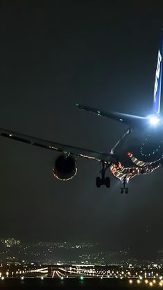 an airplane is taking off from the runway at night with its landing gear down and lights on