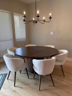 a dining room table with six chairs and a chandelier hanging from the ceiling