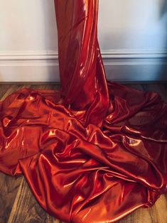 a red cloth is laying on the floor in front of a white wall and wooden floors