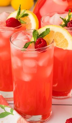 three glasses filled with lemonade and raspberries