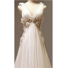 a white wedding dress with flowers on the front and back, sitting on a mannequin