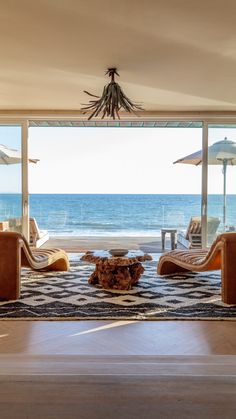 an open living room with chairs and umbrellas on the beach view from it's windows