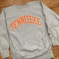 "This piece is a vintage Champion Reverse Weave crewneck sweater from the 1990s for the University of Tennessee Volunteers, also known as the Vols. This heathered grey pullover sweatshirt has a nice big Tennessee spell out on the front in orange and a little embroidery of the Champion logo at the wrist.  -Made in USA -One small yellow stain on the sleeve (pictured) Tag Size: XL, fits much smaller *refer to measurements for true fit* Pit to Pit: 21\" Length: 28.5\" Please also assess the photos and measurements carefully using your own personal judgement as we do not accept returns. Keep in mind that this is a piece of vintage clothing that may hold a residual scent from its past. While we wash all of the clothing we sell (except for certain items which are steam cleaned) we cannot guarante Vintage Fall Sweater With Letter Print, Vintage Letter Print Sweater For Fall, Throwback Letter Print Sweatshirt For Fall, Vintage Crew Sweatshirt With Lettering, Vintage Crew Neck Sweatshirt With Lettering, 90s Style Crew Neck Top For Fall, Vintage Gray Crew Sweatshirt, Vintage Gray Crew Neck Sweatshirt, Retro Crew Neck Sweater With Letter Print