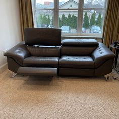 a brown leather couch sitting in front of a window