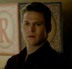 the young man is staring at something in front of him and his name on the wall behind him