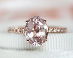 a pink diamond ring sitting on top of a white cloth