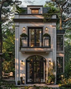 a white house with lots of windows and balconies on the second story, surrounded by trees