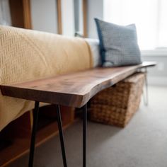 a wooden bench sitting in front of a window next to a basket on the floor