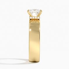 a yellow gold ring with a princess cut diamond in the center, on a white background