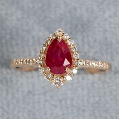 a close up of a ring with a red stone in the middle and white diamonds around it