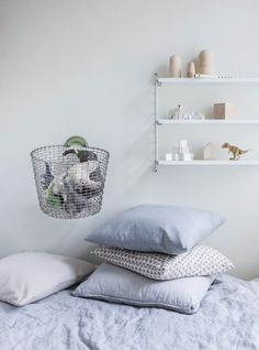 three pillows stacked on top of each other in front of a white wall with shelves