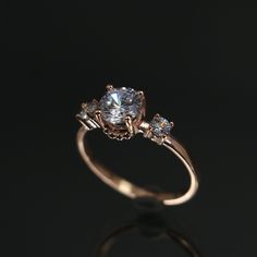 an engagement ring with three diamonds on it's side and the center stone in gold