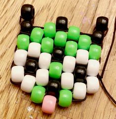 a cell phone case made out of plastic beads and black, white, and green cubes