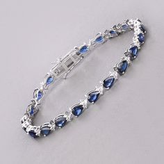 14k Gold Blue Sapphire Tennis Bracelet, Genuine Blue Sapphire Pears and Diamond White Gold Bracelet for Women, September Birthstone Bracelet Indulge in the opulence of this 8.82 carat genuine pear blue sapphire tennis bracelet, crafted in 14K white gold. Enhanced with 0.50 carats of genuine round white diamonds, this bracelet is perfect for celebrating September birthdays. Its exquisite design adds a touch of elegance to any ensemble. Product Details:  14K White Gold Item Type: Bracelet Gross Wt: 10.98 Gemstone Wt: 8.82 ctw Diamond Wt: 0.50 ctw Total Stone Wt: 9.32 ctw Finish: Fine Finish Product Style: Tennis Bracelet Chain Type: No Chain Type Clasp: Box With Tongue And Safety Clasps Total Qty Of Stones: 84 Height: 4.06 MM Width: 4.83 MM Length: 7.00 Inches Primary Stone Color: Blue Birth Sapphire Gemstone Tennis Bracelet With Oval Shape, Elegant Blue Sapphire Tennis Bracelet, Blue Sapphire Gemstone Tennis Bracelet, Classic Sapphire-colored Cubic Zirconia Bracelets, Elegant Blue Multi-stone Bracelet, Gold Bracelet For Women, White Gold Bracelet, 18k Gold Jewelry, Aquamarine Jewelry