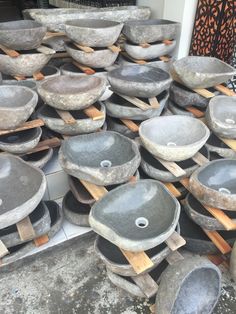 many stone bowls are stacked on wooden boards