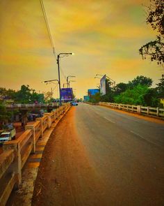 an empty street with cars parked on the side and buildings in the background at sunset