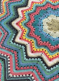 a crocheted blanket is displayed on a tablecloth with an image of a flower in the center