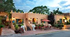 an adobe - style house is lit up at night with lights on the windows and patio furniture