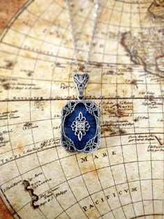 This is a true to period art deco style pendant with an antique piece of blue camphor glass which is approximately 100 years old! The piece is a beautiful, detailed filigree style and the center is adorned with a pave set diamond accent. The necklace is 18" long and comes with an easy-to-use strong trigger clasp (lobster claw). This is a great example of a period piece and would be a great addition to your Art Deco collection.  I do have some other pieces available as well and matching bracelets and earrings so be sure to check out some of my other listings too.! Thanks for looking and if you have any questions, always feel free to ask :). fp383srb Art Deco Vintage Charm Jewelry As Gift, Art Deco Vintage Charm Jewelry Gift, Art Deco Style Vintage Charm Jewelry Gift, Vintage Blue Cabochon Jewelry, Blue Vintage Cabochon Jewelry, Art Deco Jewelry With Rectangular Pendant As Gift, Art Deco Jewelry With Rectangular Pendant For Gift, Vintage Engraved Rectangular Pendant Necklace, Vintage Rectangular Locket Pendant