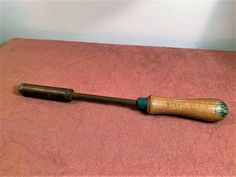 an old wooden baseball bat laying on top of a pink blanket next to a white wall