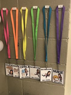 there are several lanyards hanging on the wall with name tags attached to them