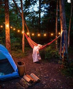 a woman is walking through the woods with a hammock in front of her