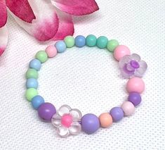 Add a touch of sweetness and whimsy to your little one's outfit with this Handmade Children's Bead Bracelet. The bracelet features colorful floral beads that are perfect for adding a pop of color to any ensemble. Handcrafted with care, this bracelet is not only stylish but durable for even the most active little ones. This charming accessory is sure to become a favorite in their jewelry collection and makes a perfect gift for any occasion. Bangle Bracelets With Charms, Bead Bracelet, Bangle Bracelets, Color Pop, Jewelry Collection, Jewelry Bracelets, Floral Design, Bangles, Charms