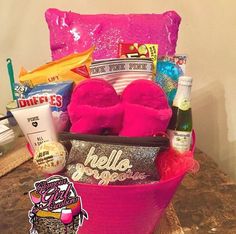 a pink basket filled with lots of goodies on top of a table next to a pillow