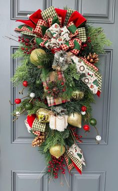 a christmas wreath hanging on the front door with evergreen, pine cones and plaid ribbon