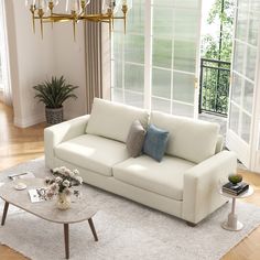 a living room filled with furniture and a chandelier hanging from the ceiling over a white rug