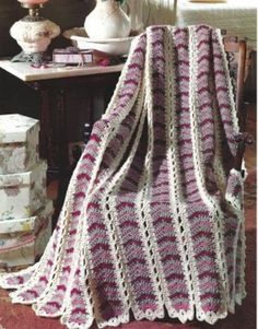 a crocheted blanket sitting on top of a wooden chair next to a table