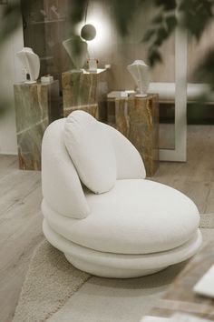 a white chair sitting on top of a wooden floor next to a mirror and vases