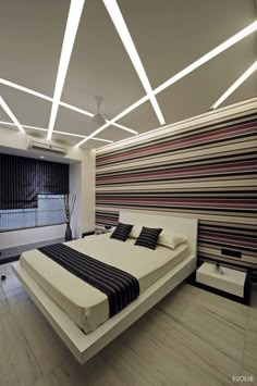 a modern bedroom with striped wallpaper and white bed in the center, along with wooden flooring